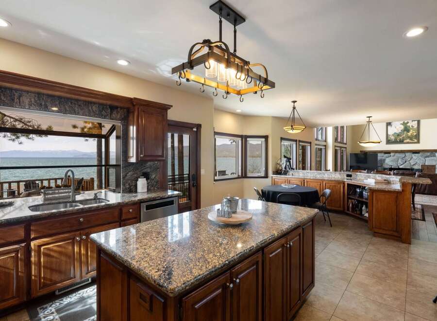 Experience breathtaking lake views from this stunning kitchen, featuring a large island with granite countertops and rich wood cabinetry.