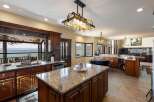 Experience breathtaking lake views from this stunning kitchen, featuring a large island with granite countertops and rich wood cabinetry.