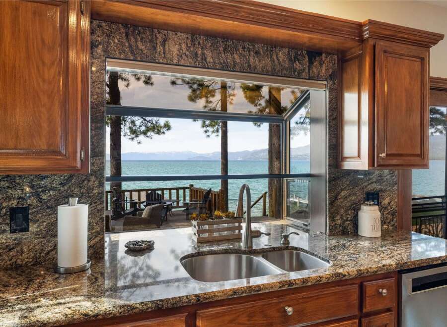 Experience breathtaking lake views from this stunning kitchen, featuring a large pass-through window that seamlessly connects indoor and outdoor living spaces.