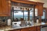 Experience breathtaking lake views from this stunning kitchen, featuring a large pass-through window that seamlessly connects indoor and outdoor living spaces.