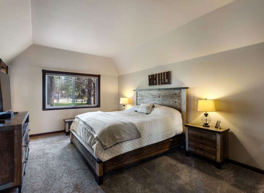 Experience rustic charm in this inviting bedroom, featuring a queen-size bed with a distressed wood headboard and cozy bedding.