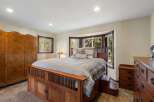 Experience rustic charm in this inviting bedroom, featuring a substantial wooden bed frame with integrated storage and a beautiful bay window overlooking lush greenery.