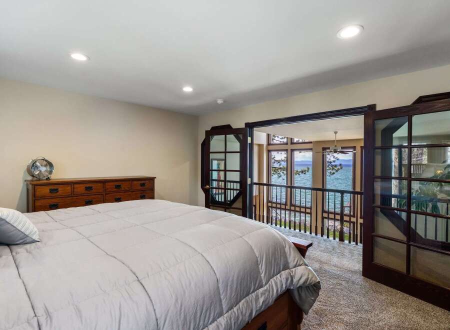 Wake up to breathtaking lake views from this stunning bedroom, featuring a spacious master suite with direct access to a private balcony.