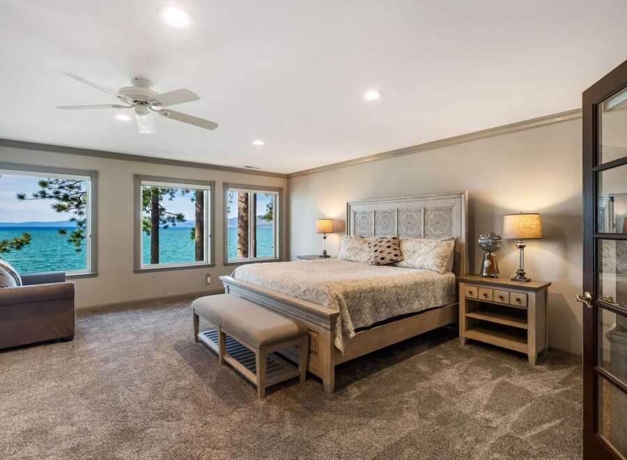 Experience breathtaking lake views from this luxurious master bedroom, featuring a spacious king-size bed and a comfortable seating area.