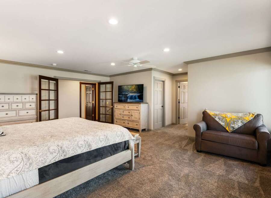 Experience luxury and comfort in this spacious master bedroom, featuring a king-sized bed with a plush comforter and a large dresser with a mounted television.