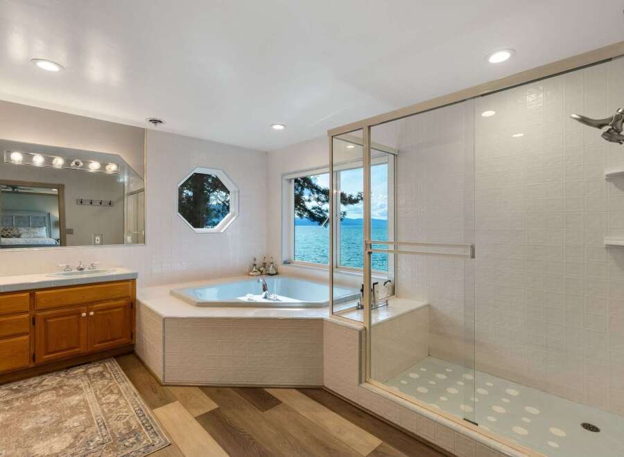 Experience luxury in this stunning bathroom featuring a spacious corner jacuzzi tub with breathtaking lake views.