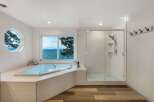 Experience breathtaking lake views from this luxurious bathroom, featuring a spacious soaking tub and a separate glass-enclosed shower.