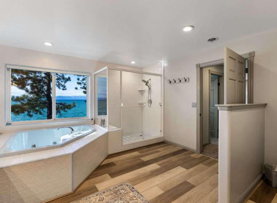 Indulge in luxury with this stunning bathroom featuring a spacious jacuzzi tub offering breathtaking lake views.