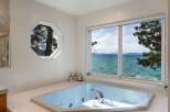 Indulge in ultimate relaxation in this luxurious bathroom featuring a spacious jacuzzi tub with stunning panoramic views of the serene lake and distant mountains.