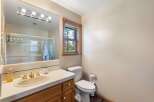 This charming bathroom features a spacious vanity with a gold-toned sink and faucet, complemented by a large mirror with a modern light fixture.