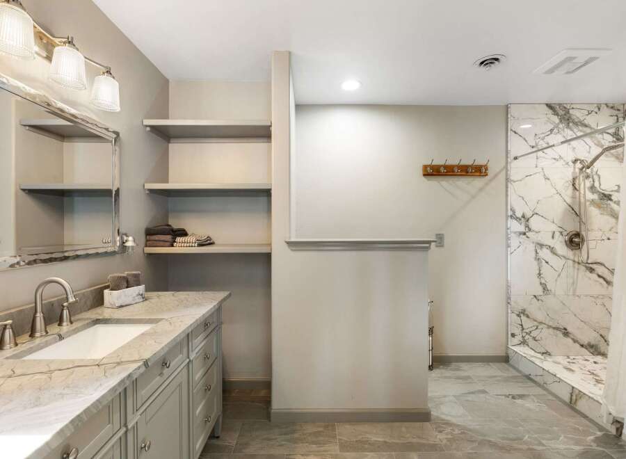 Experience modern luxury in this stunning bathroom featuring a sleek vanity with a marble countertop and a spacious walk-in shower with elegant marble tile.