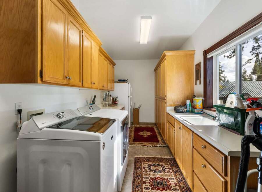 This spacious laundry room features ample storage with beautiful oak cabinetry, perfect for organizing all your cleaning supplies.