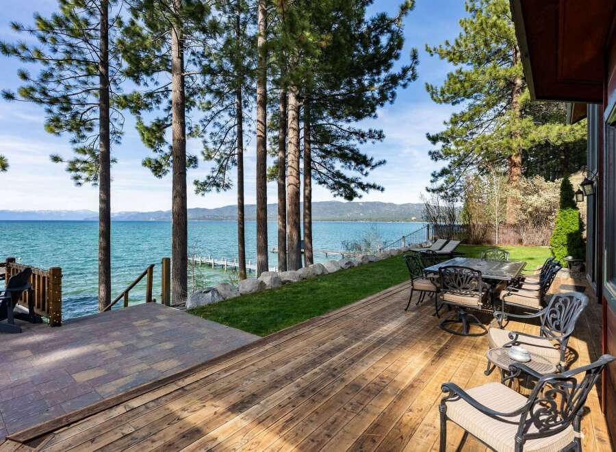 Enjoy breathtaking lake views from this stunning property featuring a spacious wooden deck perfect for outdoor entertaining.