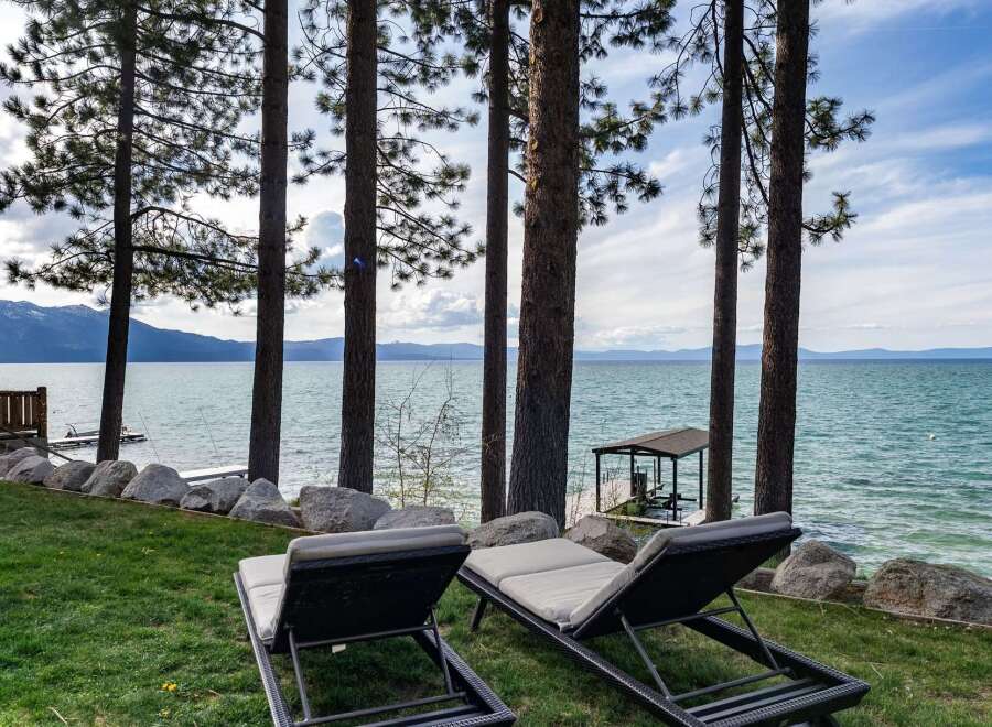 Enjoy breathtaking lake views from this stunning property, featuring two comfortable lounge chairs perfect for soaking up the sun.