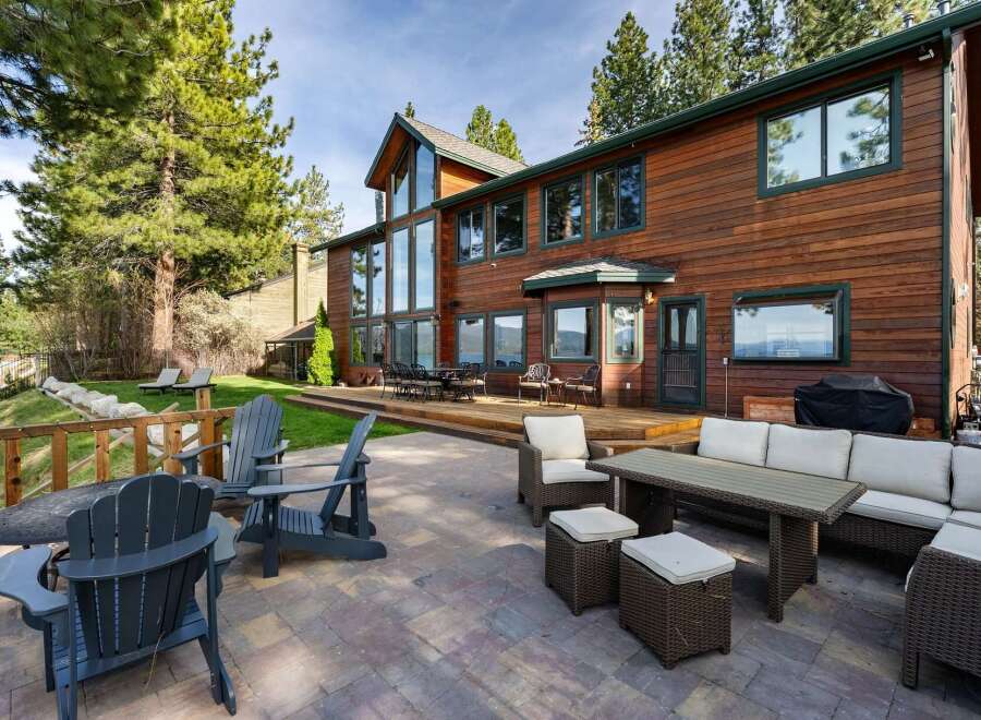 Experience luxury living in this stunning lakefront property, featuring a spacious wooden deck and a beautifully paved patio perfect for outdoor entertaining.