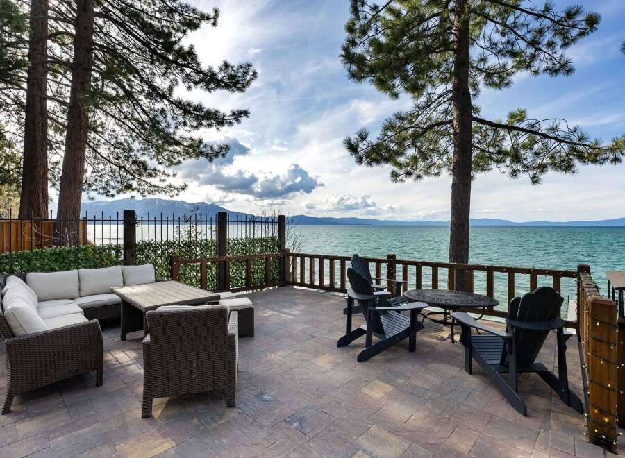Enjoy breathtaking lake views from this stunning patio, complete with comfortable wicker sectional seating and a dining table.