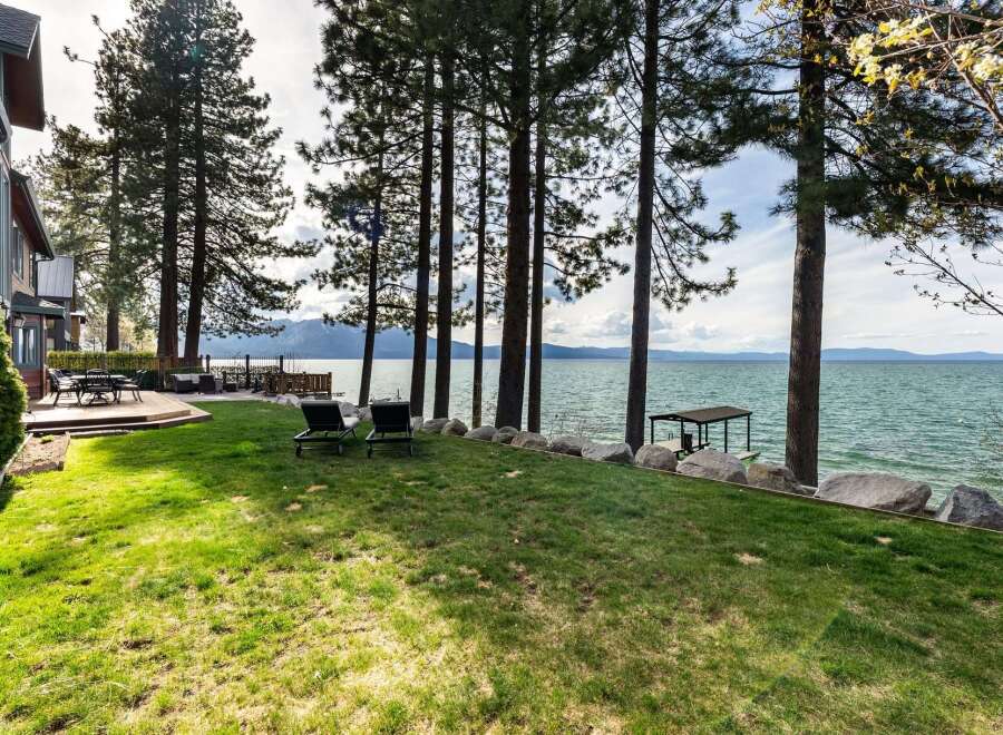 Experience luxurious lakeside living with this stunning property featuring a spacious deck and manicured lawn leading to the water's edge.