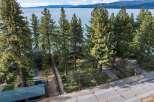 Experience serene lakefront living with this stunning property, nestled amongst mature pine trees and offering breathtaking views of the water and distant mountains.
