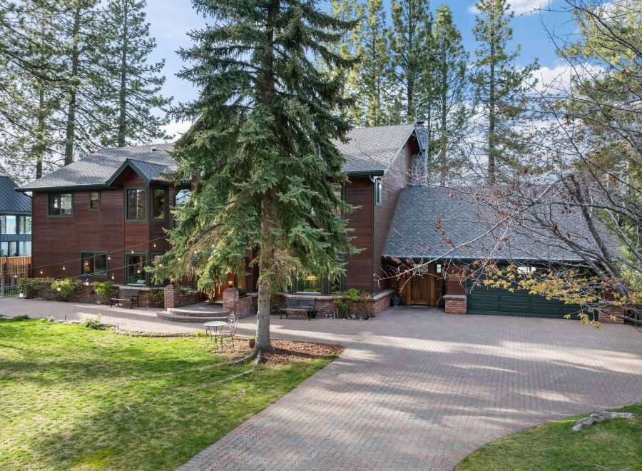 Nestled amongst tall pine trees, this stunning multi-story home offers a warm and inviting ambiance with its rich wood exterior and expansive grounds.