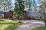 Nestled amongst tall pine trees, this stunning multi-story home offers a warm and inviting ambiance with its rich wood exterior and expansive grounds.