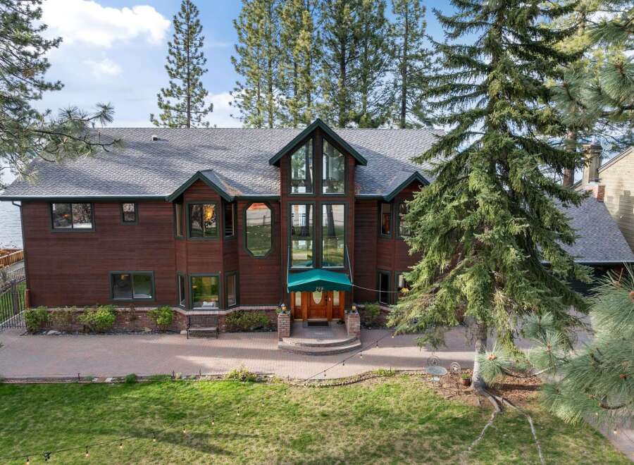 Experience luxury living in this stunning lakefront property, featuring a grand wooden exterior and expansive windows offering breathtaking water views.