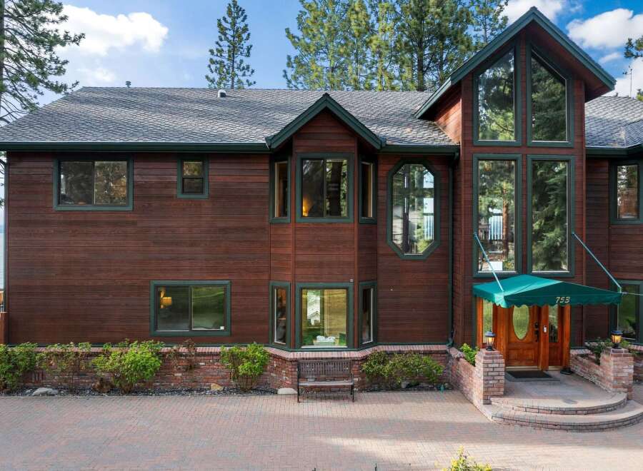 Experience luxury living in this stunning lakefront property, boasting a grand wooden exterior and expansive windows that capture breathtaking views.