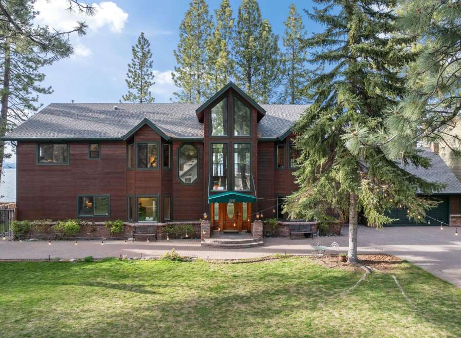 Experience luxury living in this stunning lakefront property, featuring a grand wooden exterior and expansive windows that offer breathtaking views.