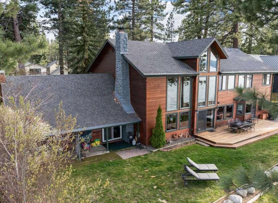 Experience luxury lakeside living in this stunning wood-sided home, featuring a grand stone chimney and expansive windows that offer breathtaking water views.