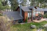 Experience luxury lakeside living in this stunning wood-sided home, featuring a grand stone chimney and expansive windows that offer breathtaking water views.