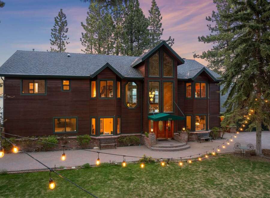 Experience luxury living in this stunning lakefront property, featuring a grand wooden exterior and expansive windows that capture breathtaking views.