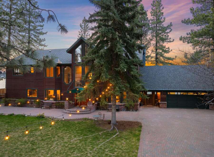 Experience luxury living in this stunning lakefront property, featuring a grand wooden exterior and expansive windows that capture breathtaking sunset views.