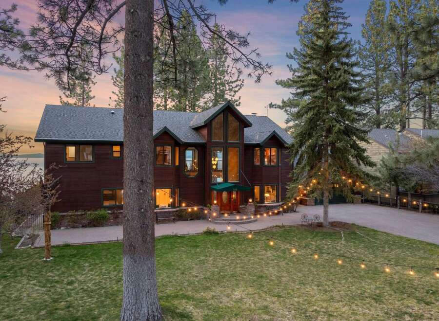 Experience luxury living in this stunning lakefront property, featuring a grand wooden exterior and expansive windows that capture breathtaking views.