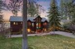 Experience luxury living in this stunning lakefront property, featuring a grand wooden exterior and expansive windows that capture breathtaking views.