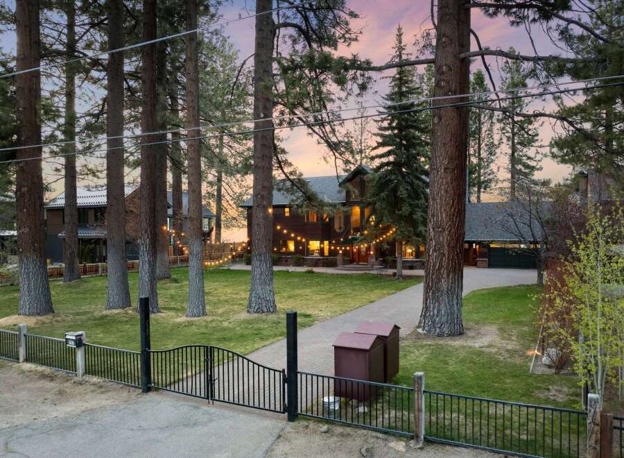 Experience luxury living in this stunning mountain home, nestled amongst towering pine trees and featuring a charming string light ambiance.