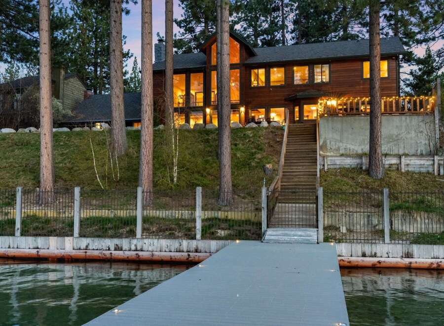 Experience lakeside luxury in this stunning wooden home, featuring expansive windows that offer breathtaking water views.