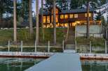 Experience lakeside luxury in this stunning wooden home, featuring expansive windows that offer breathtaking water views.