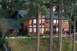 Nestled among towering pine trees, this stunning wooden lodge-style home offers breathtaking views through its expansive windows.