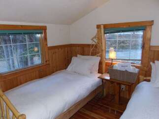 Experience cozy comfort in this charming cabin bedroom, featuring two inviting twin beds perfect for a restful night's sleep.
