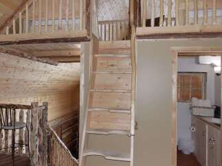 Experience rustic charm in this log cabin featuring a unique loft space accessible by a wooden staircase.