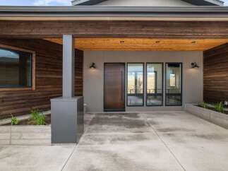 Experience modern living with this stunning home featuring a sleek wood-paneled exterior and a welcoming covered entryway.