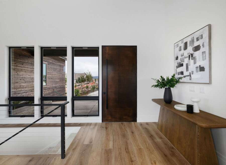 Step into a modern entryway featuring a striking dark wood door and expansive windows that flood the space with natural light.