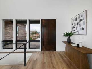 Step into a modern entryway featuring a striking dark wood door and expansive windows that flood the space with natural light.