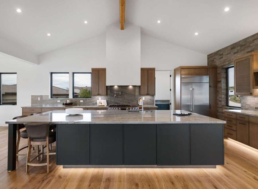 Experience luxury in this modern kitchen, featuring a spacious island with a sleek waterfall countertop and dark cabinetry.