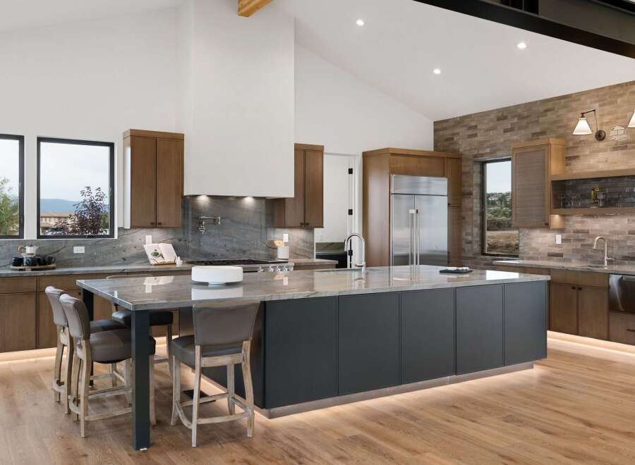 Experience luxury in this modern kitchen featuring a large island with seating, sleek dark cabinetry, and a striking marble countertop.