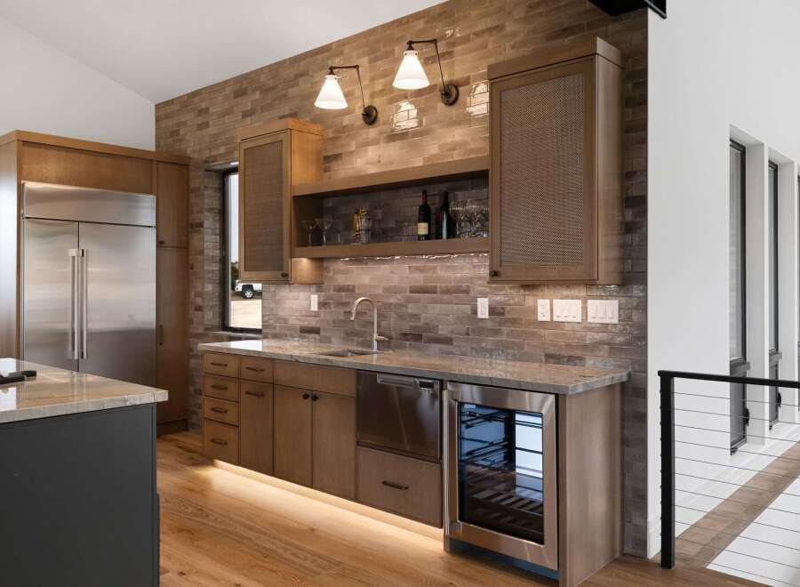 Experience luxury living with this modern kitchen featuring a sleek stainless steel refrigerator and a built-in wine cooler.