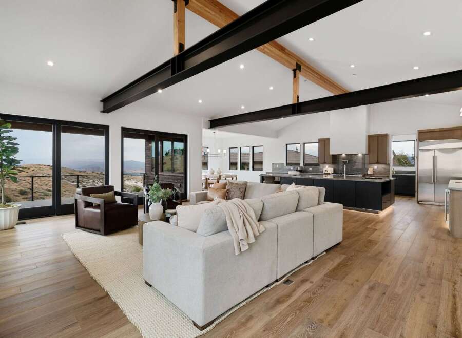 Experience modern luxury in this open-concept living space, featuring a spacious sectional sofa and stunning panoramic views through large sliding glass doors.