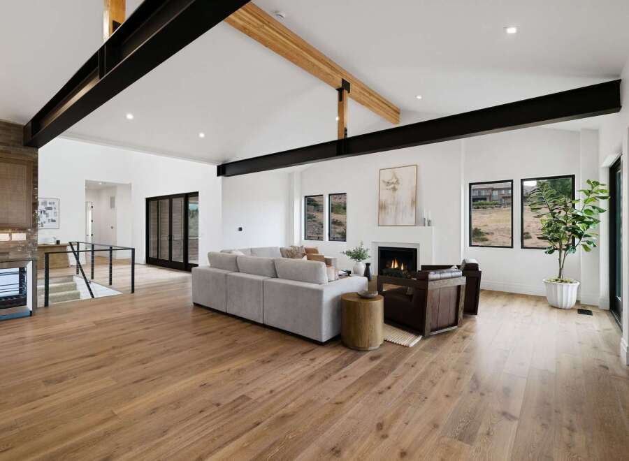 Experience modern luxury in this stunning living room, featuring soaring vaulted ceilings with exposed black steel beams and natural wood accents.