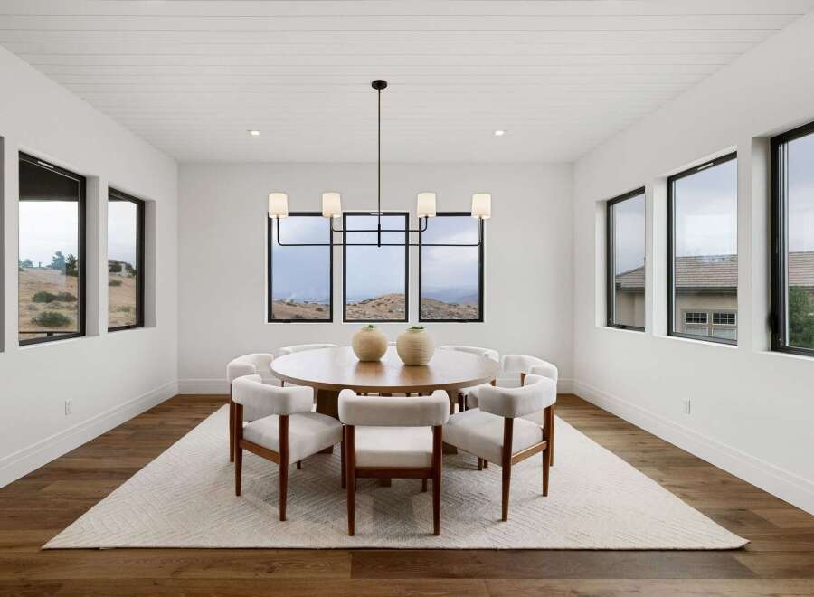 Experience elegant dining in this modern space, featuring a round wooden table surrounded by plush white chairs.