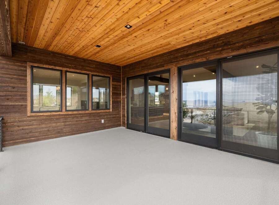 Experience seamless indoor-outdoor living with this stunning covered patio, featuring a warm wood-paneled ceiling and rich wood siding.
