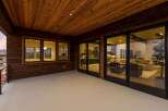 Experience seamless indoor-outdoor living with this stunning covered patio, featuring a warm wooden ceiling and expansive glass doors that open into a beautifully appointed living space.